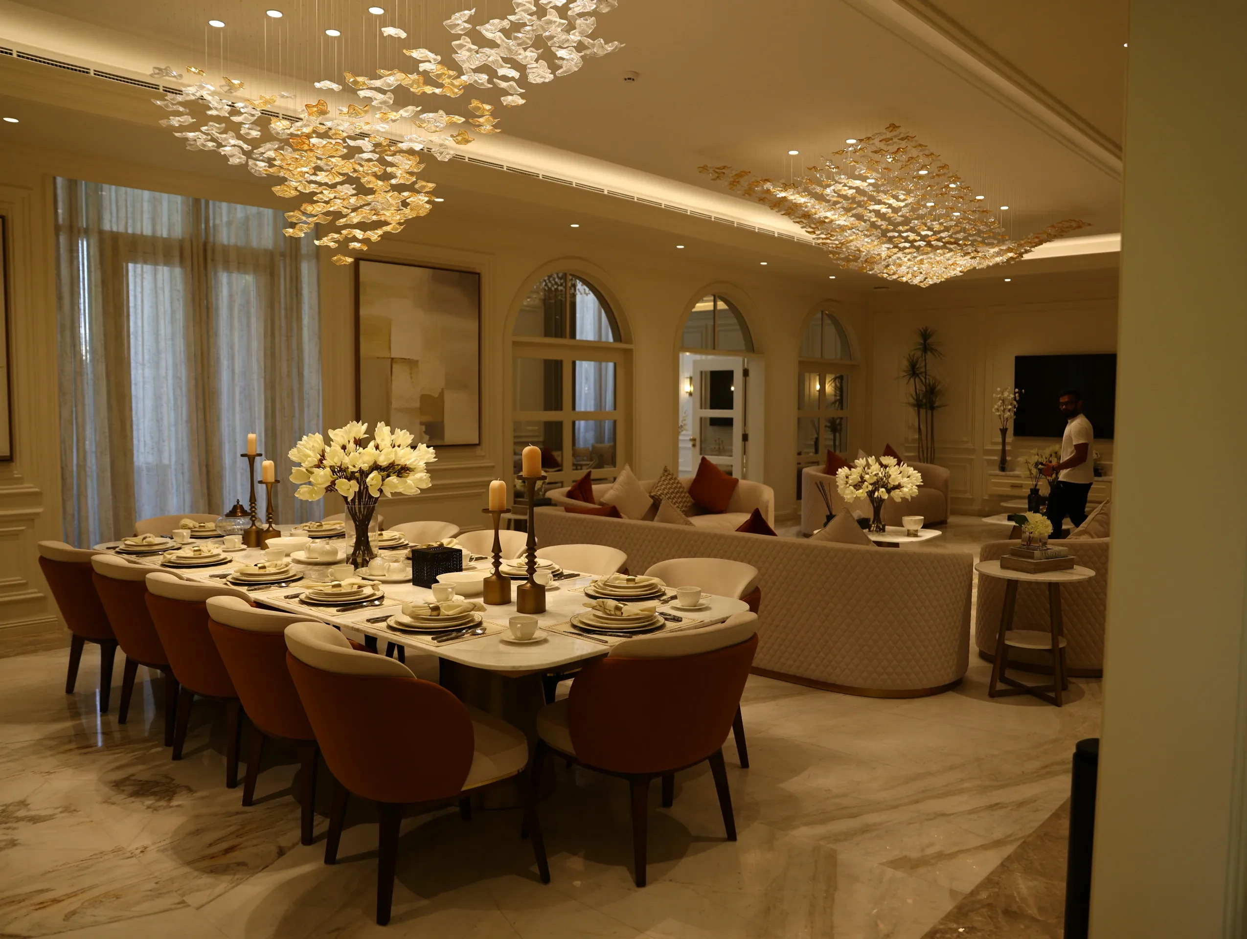 An elegant living room with sculptural seating, warm accents and a crystal chandelier
